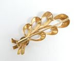 a gold leaf brooch on a white surface