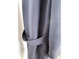 the back of a coat hanging on a hanger in front of a white wall