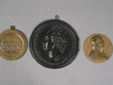 three gold and silver medallions of a woman and a man