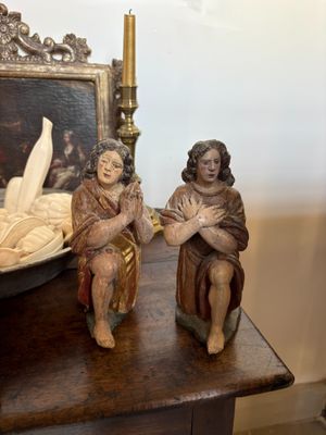 two figurines of people sitting on a table next to a bowl of fruit
