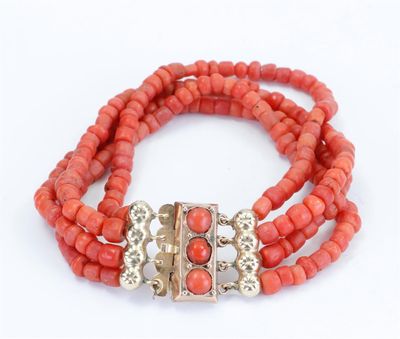 a close up of a bracelet with coral beads on a white background