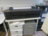 une imprimante posée sur un bureau, à côté d'une commode à tiroirs