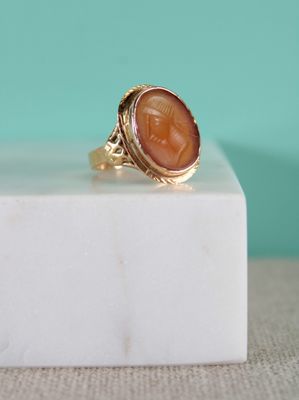 un gros plan d'une bague en or sur laquelle est gravé un visage