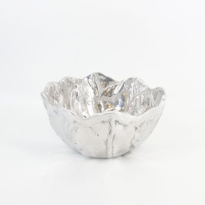 un bol en argent posé sur une surface blanche