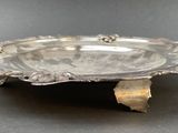 an antique silver plate on a stand on a table