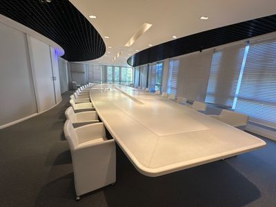 une photo d'une salle de réunion avec une longue table et des chaises