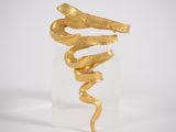 a gold snake sculpture on a clear base with a white background
