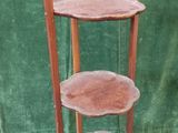 a three tiered wooden stand with a green curtain in the background