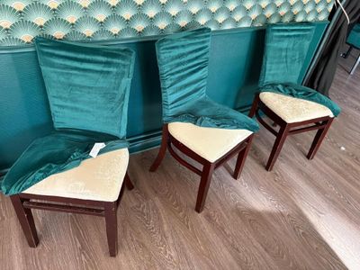 three chairs with green velvet upholstered seats in front of a green wall