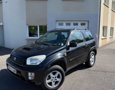 une photo d'une Toyota RAV noire garée devant un immeuble