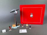 toy figurines of people playing with a red box and a lamp