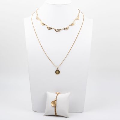 un mannequin blanc portant un collier, un bracelet et une bague en or