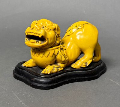 yellow statue of a lion on a black base on a gray surface