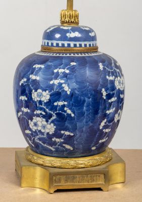 a blue and white vase with a gold base on a table