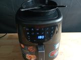 an air fryer sitting on top of a wooden table next to a black wall