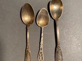 three silver spoons sitting on top of a table next to each other