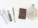 a bottle, knife, spoon, and spoon rest on a white surface