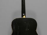 a black acoustic guitar hanging on a wall in a room