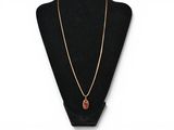 a gold necklace with a red stone pendant on a black mannequin