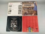 three beatles abbey road records on a table with a woman in a blue dress