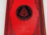 a red book with a black cover and a monogram on it