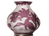 un vase violet orné de fleurs, posé sur une surface blanche