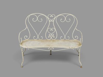 une image représentant un banc en fer forgé blanc sur fond gris