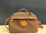 un petit sac marron muni d'une poignée en cuir, posé sur une table en bois
