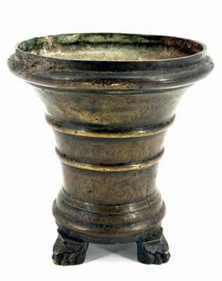 un grand vase en métal posé sur un socle, sur une surface blanche