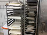 several trays of food are stacked on a metal rack in a kitchen