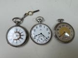trois montres de poche différentes posées sur une table