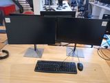 two computer monitors and a keyboard on a desk