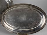 two silver trays with handles and handles on a white surface