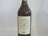 bottle of red wine on a white table with a glass of wine in the background