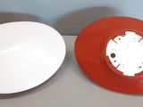 une horloge rouge et blanche et une assiette blanche posées sur une table