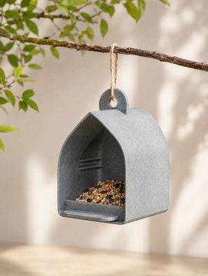 un gros plan d'une mangeoire à oiseaux suspendue à une branche d'arbre