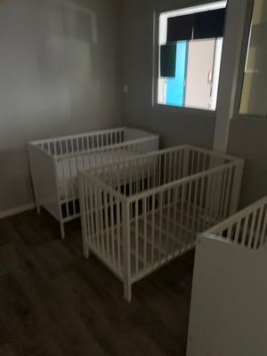 deux lits bébé dans une petite pièce dotée d'une fenêtre