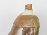a brown and white vase with a bottle on top of it