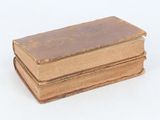 three old books stacked on top of each other on a white surface