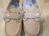 beige leather shoes with buckles on a wooden floor next to a tag