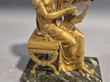a gold statue of a woman playing a harp on a marble base