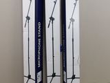 two boxes of microphone stands sitting on top of a table