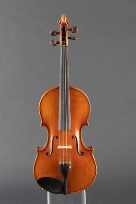 an old violin sitting on a stand against a gray background