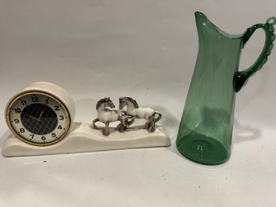 un pichet en verre vert et une horloge posés sur une table blanche