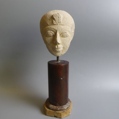sculpture représentant une tête de femme, posée sur un socle en bois