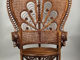 an antique wicker peacock chair with a wooden seat and foot rest