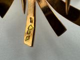 a close up of a gold plated clock on a white surface
