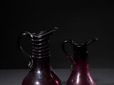 pair of red glass vases sitting on a table in a dark room