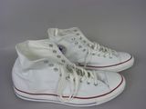 Des baskets Converse blanches avec des lacets rouges et blancs sont posées sur une surface grise
