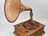 un vieux gramophone posé sur un support en bois, sur fond blanc